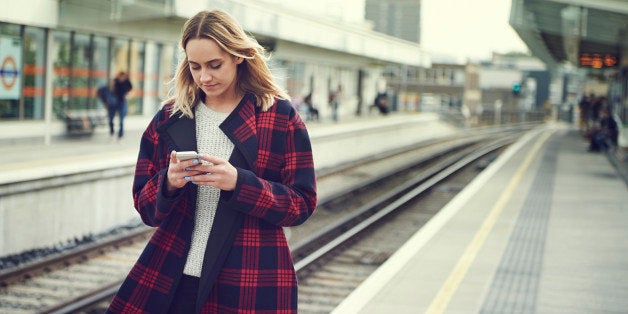 Woman with smart phone in train station