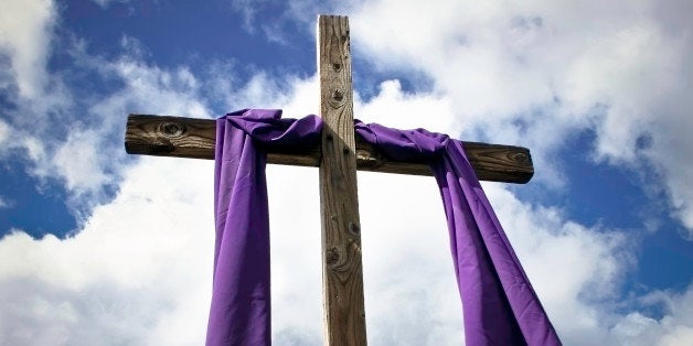 Back lit cross framed by bright sky and billowing clouds. Photo shot during the season of lent when the cross is to be veiled.