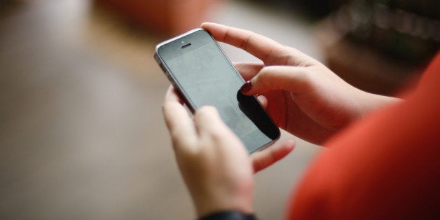 Close up shot of woman's manicured hand as she uses a handphone