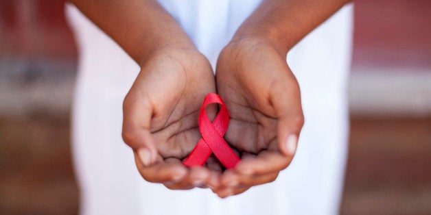 Child's hands holding an HIV awareness ribbon, Cape Town, South Africa