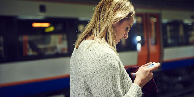 Woman with smart phone in train station
