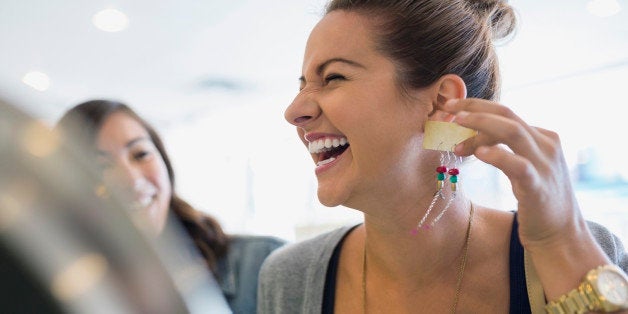 Laughing woman holding earrings in shop