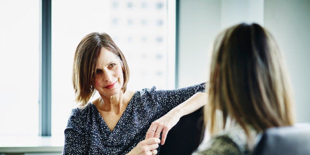 Mature businesswoman in discussion with female colleague at conference table in office