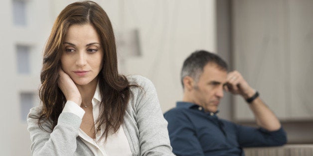 Sad Couple Sitting On Couch After Having Quarrel