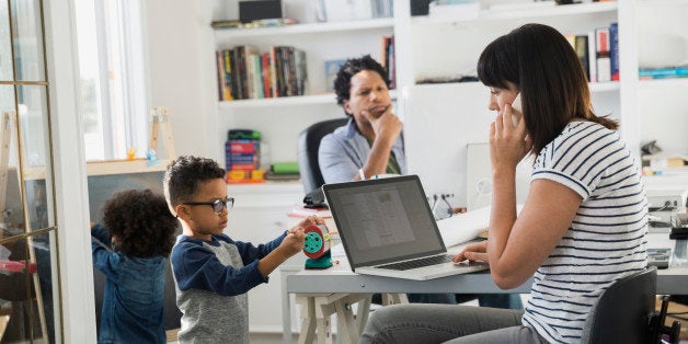 Parents working in home office with children playing