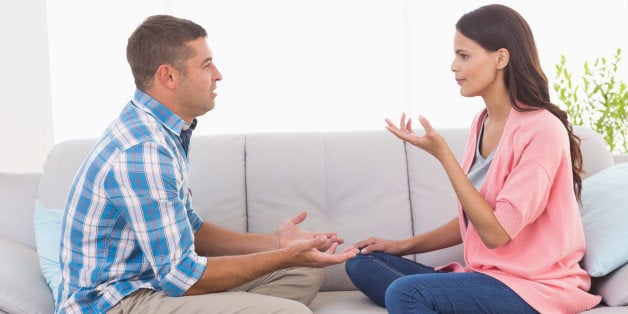 Side view of man and woman arguing while sitting on sofa at home