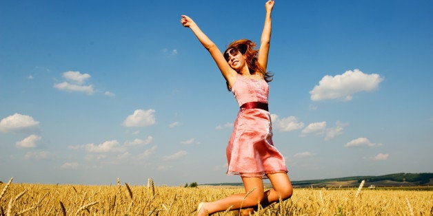 Happy woman jumping in golden field