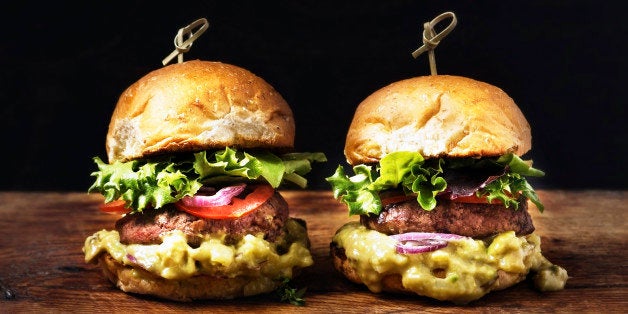 Two burgers on a rustic wooden table