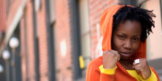 Woman in boxing stance with brick building in background