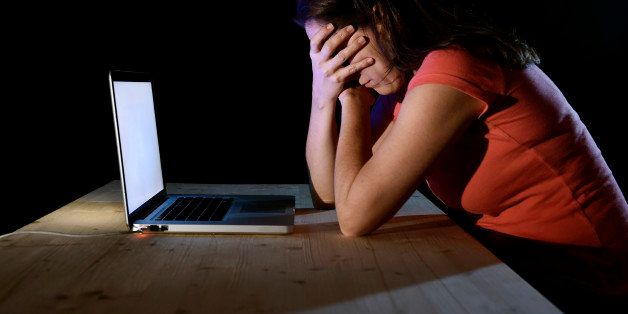 young desperate and depressed freelance worker or student woman working with computer laptop alone late at night in stress suffering internet bullying victim of social network