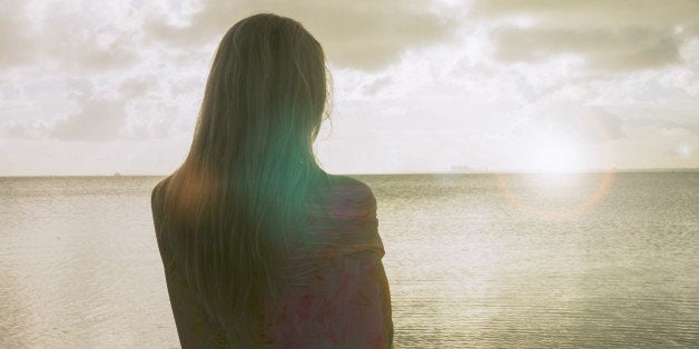 Woman on the beach watching the horizon