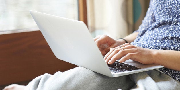 Woman using laptop at home, close up.