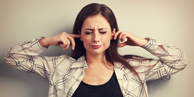 Unhappy stressed young woman not want to listen and covering the ears her fingers. Vintage toned portrait