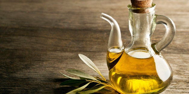 Olive oil and olive branch on the wooden table.