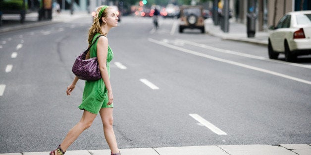 Woman walking in crosswalk in city