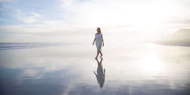 Woman walking alone on a misty beach