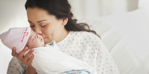 Mother in hospital bed holding newborn baby girl