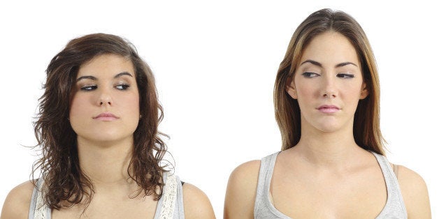 Two girls looking each other angry isolated on a white background