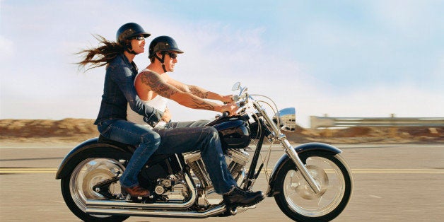 Couple on old fashioned motorbike, side view