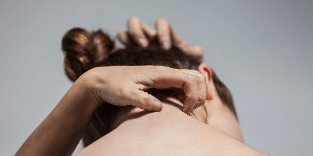 Portrait from behind of woman with head down as she is scratching at her head and neck