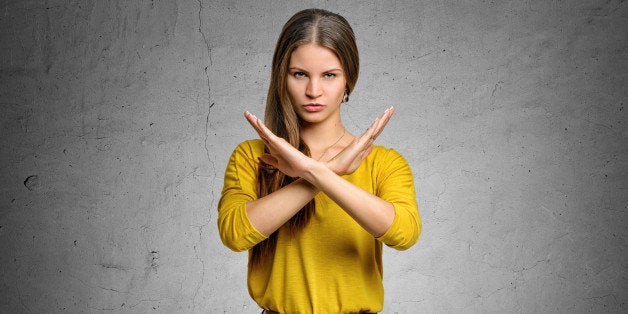 Serious young woman making X sign with her arms to stop doing something. Signs symbols, body language.