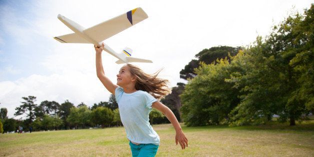 Girl, aged 10, running with a toy plane in a park