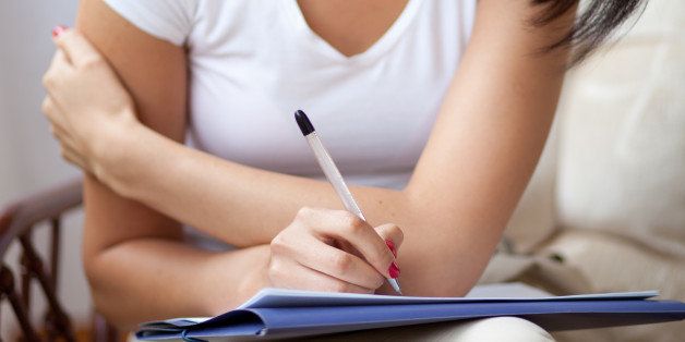 Young dark woman writing on notepad to do list at home