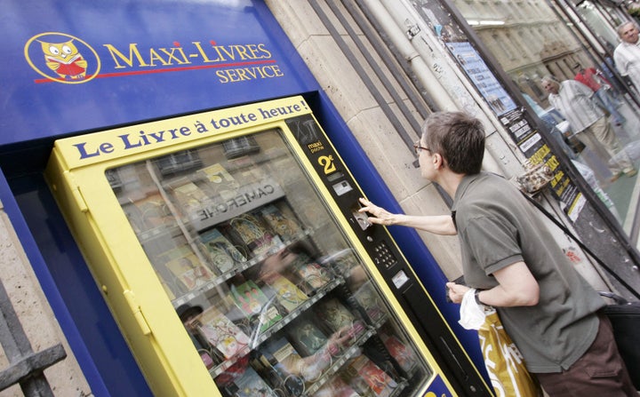 Paris, FRANCE: A young woman buys a book from a street vending machine 19 August 2005 in Paris. The company announced the installation of four distributors of pocket books in high-traffic Metro stations around the capital, plus one in the street, 19 August 2005. Maxi-Livres automats offer 25 titles among the classics, gastronomy and dictionaries at 2 euros apiece. The vending service started up in 1978, buying up publishers' stocks of surplus books for its popular bookstores. (Photo credit should read BERTRAND GUAY/AFP/Getty Images)