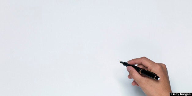 Man writing on white sheet of paper, close-up of hand