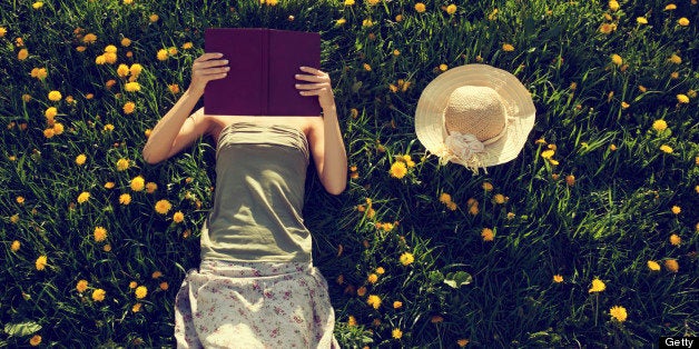 Girl lying in grass, reading a book