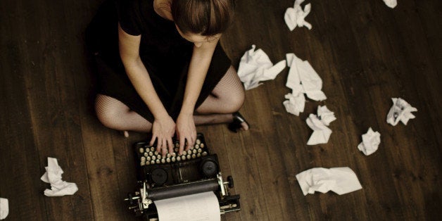 'Young woman sitting on the floor and typing, toned image, focus on the head'