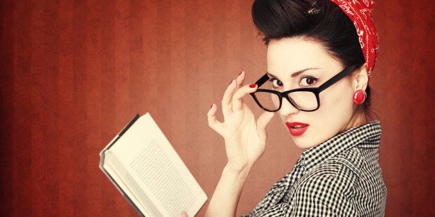 Portrait of a retro colored young brunette, reading an exciting book, looking at camera, in vintage clothes and glasses.