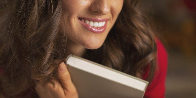 Closeup on young woman with christmas cup of hot chocolate with marshmallow hugging book