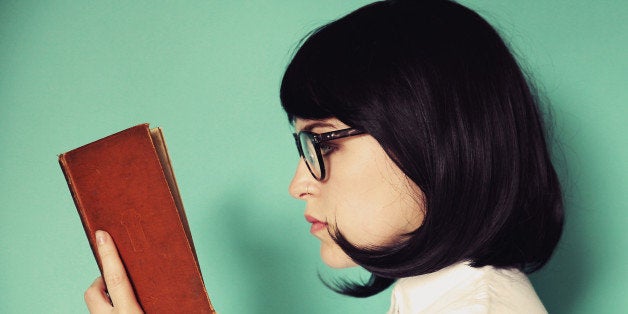 Profile of a young woman reading a book wearing glasses