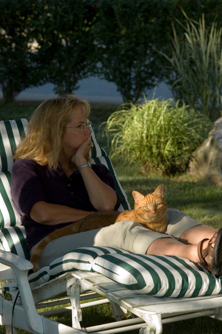 Woman with cat relaxing on a chaise lounge on a summer day.