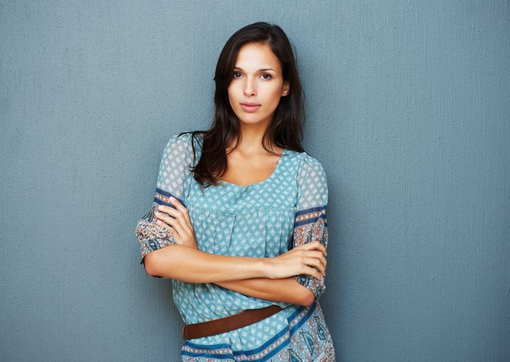 Earnest woman with arms crossed against a blue background