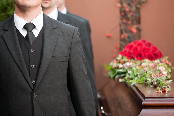 Religion, death and dolor - coffin bearer carrying casket at funeral to cemetery