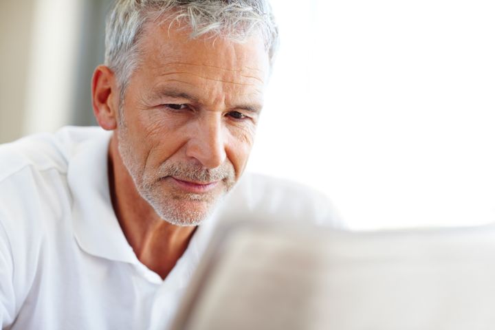 Closeup portrait of a senior man reading a newspaper - Copyspace