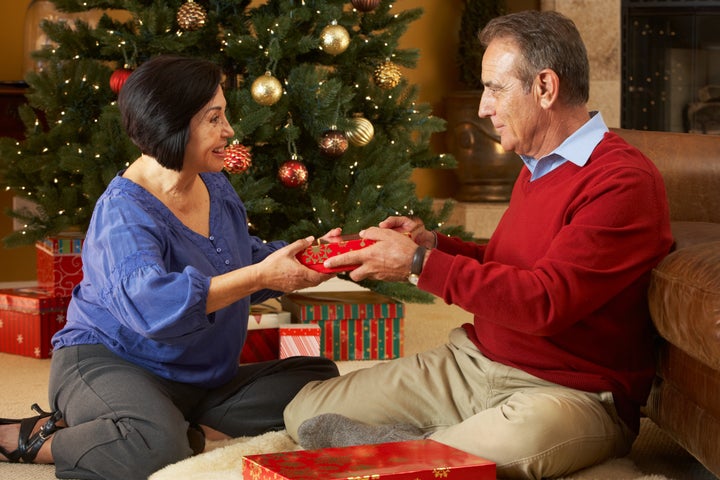 Senior Couple Exchanging Gifts In Front Of Christmas Tree