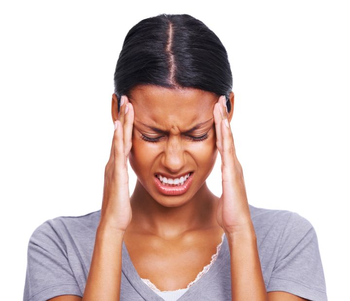 Stressed - Young woman holding head in pain over white background