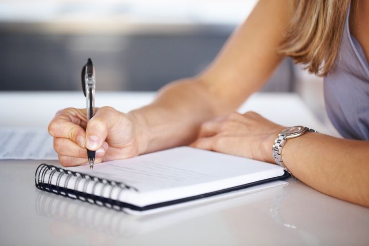 Cropped image of woman's hand with pen writing down notes