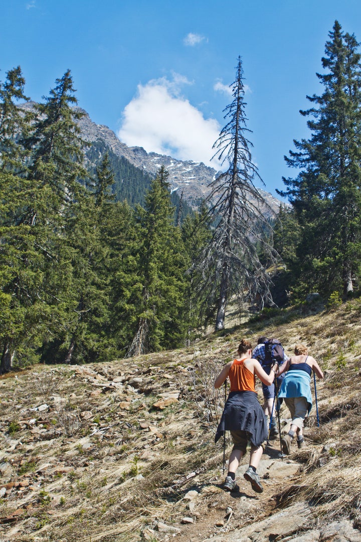 Family with senior parents and a young daughter hiking in the mountains