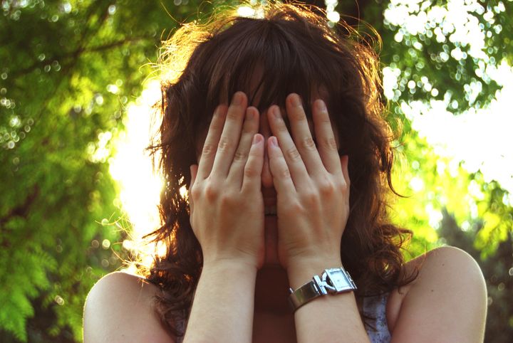 Young woman covering her face with her hands.
