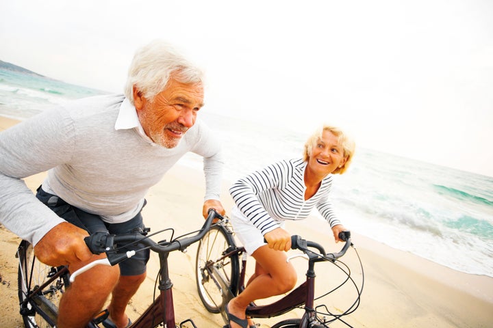 Senior couple driving bicycles on the beach