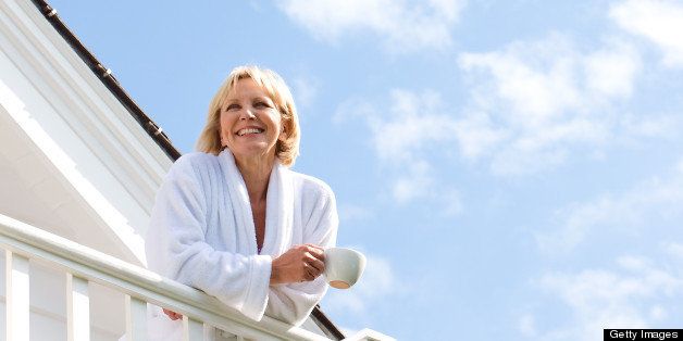 Woman in bathrobe leaning on railing drinking coffee