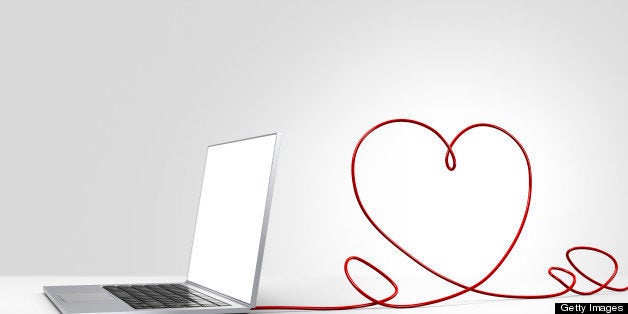 Laptop computer with a red ethernet cable forming a heart, coming out of the back on a plain background