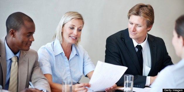 Panel of executives reading the resume of an applicant during her interview