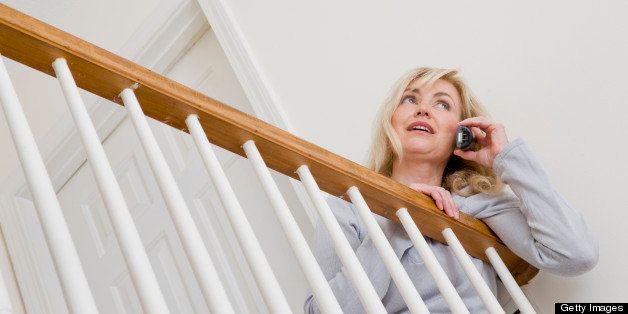 Blonde Caucasian woman, 51 years old, talking on her telephone while leaning over the balustrade