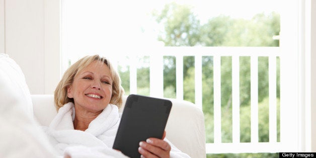 Woman reclining on sofa using digital tablet