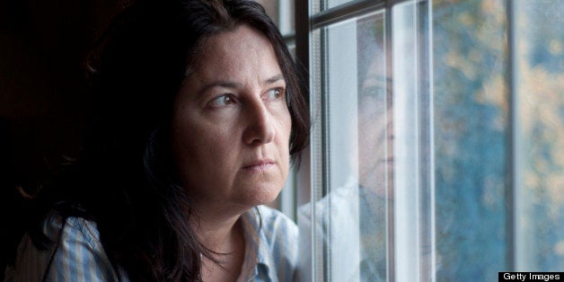 Woman looking through window, looks like she's thinking or dreaming.